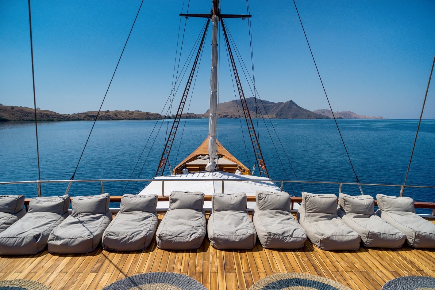 Bow sundeck of Prana by Atzaró lined with grey beanbag loungers overlooking Komodo islands