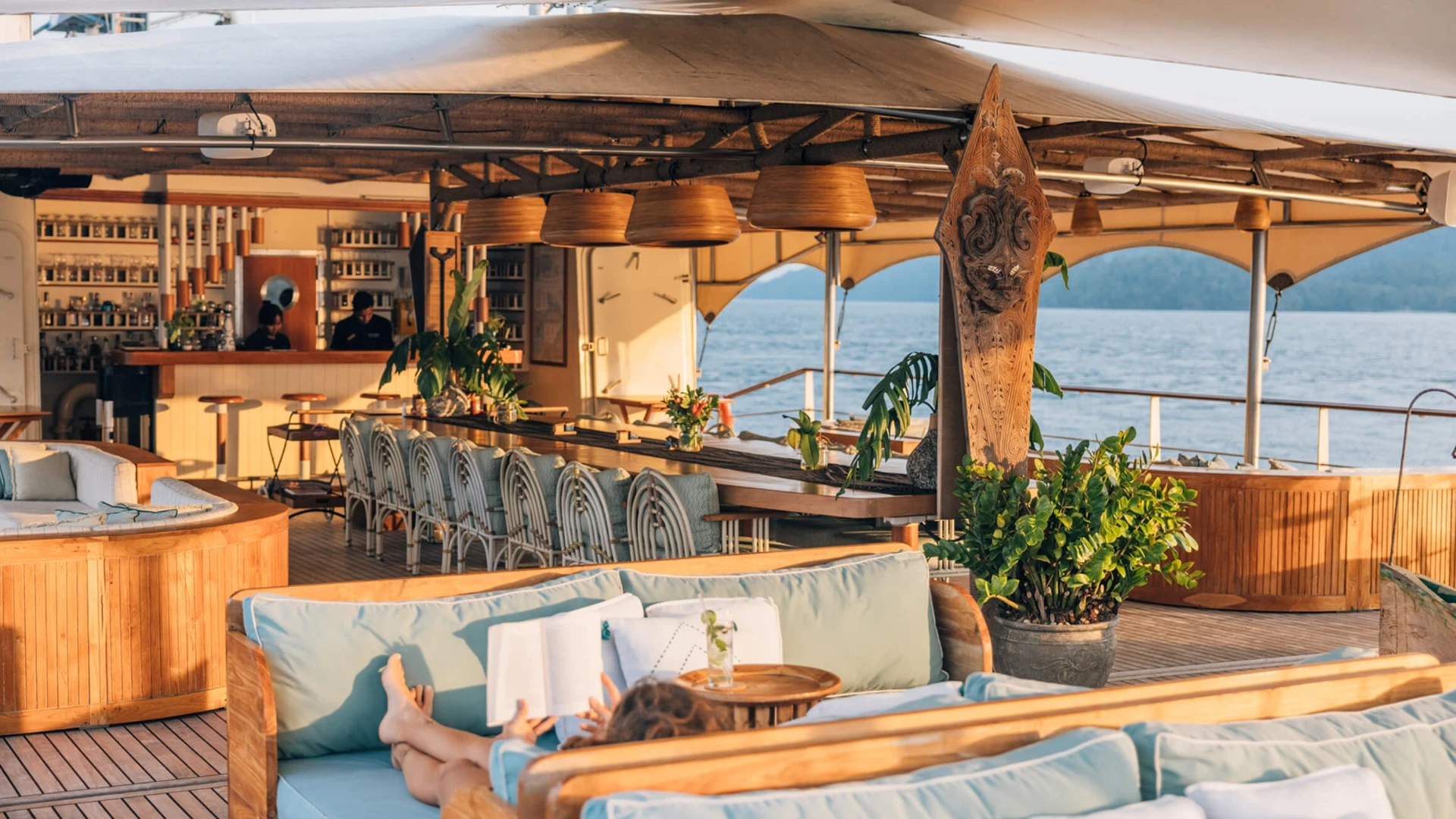Sky Lounge on Kudanil Explorer at golden hour with bar, long dining table and lounge sofas
