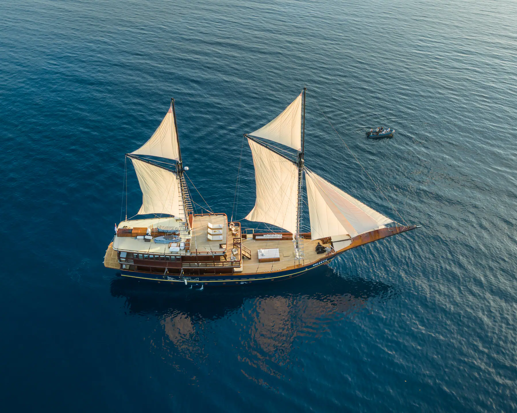 Aerial view of Celestia phinisi under full sail on open water — Raja Ampat private yacht charter